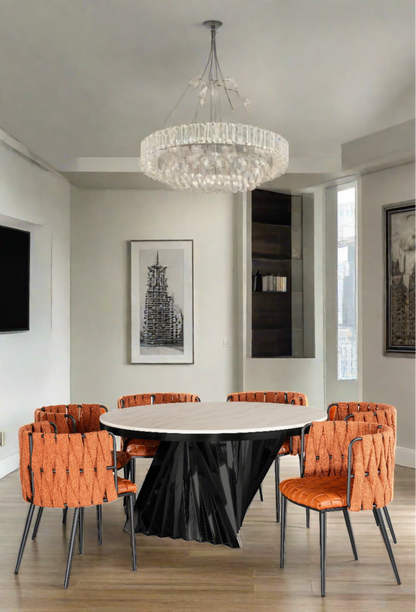 Black and white marble top round modern dining table with 8 orange curved faux leather dining chairs in orange and black